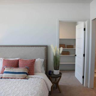 A modern, minimalist bedroom featuring a comfortable bed with decorative pillows and an open closet.