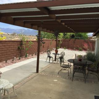 A backyard patio with outdoor furniture and a wooden pergola.