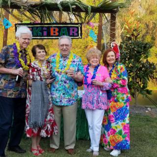 A group of people enjoying a tropical-themed party with lei necklaces and colorful attire.