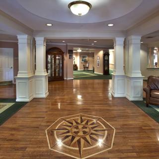 A hotel lobby featuring wood flooring with a decorative design and elegant columns.