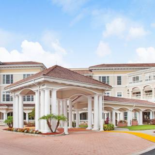 A grand residential building with an elegant columned entrance under a blue sky.