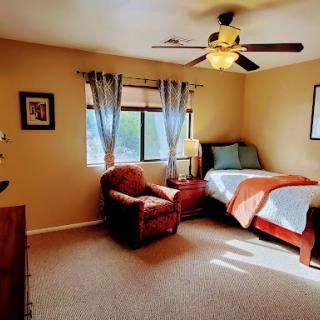 A cozy and well-lit bedroom featuring a comfortable bed, an inviting chair, and warm decor.