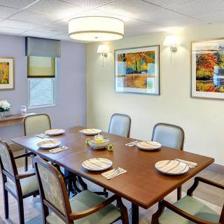 A well-decorated dining room with a wooden table and chairs, featuring wall art and modern lighting.