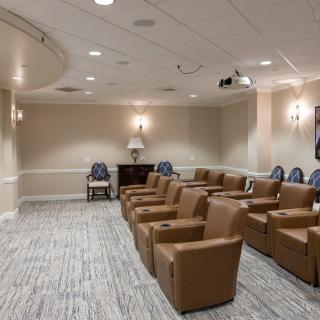 A cozy theater-style seating area with armchairs and a projector in a well-lit room.