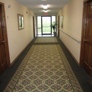 A carpeted hallway with doors on either side and a large window at the end.