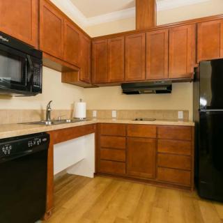 A modern kitchen with wooden cabinets and black appliances.