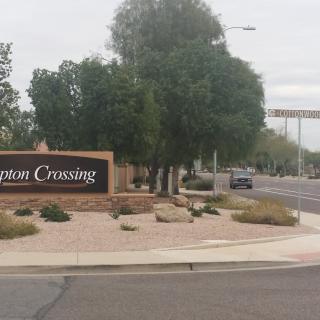 Entrance sign to a community with trees and landscaping.