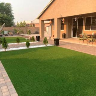 A well-maintained backyard featuring a lush green lawn and a patio area.
