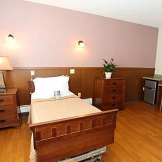A simple, well-furnished hospital room with a wooden single bed and matching furniture.