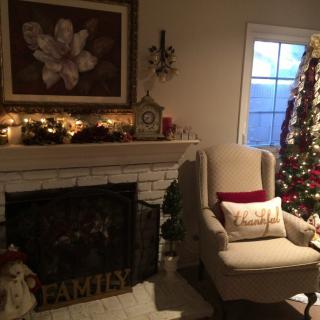 A cozy living room decorated for the holidays, featuring a warm fireplace and a beautifully adorned Christmas tree.