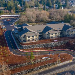 An aerial view of a large building surrounded by roads and trees in a residential area.