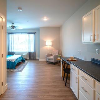 A modern studio apartment with a cozy bedroom, a kitchenette area, and stylish furniture.