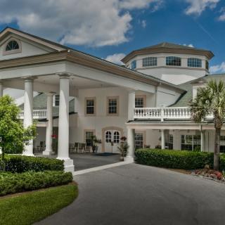 A grand, luxurious mansion with prominent white columns and a circular driveway.