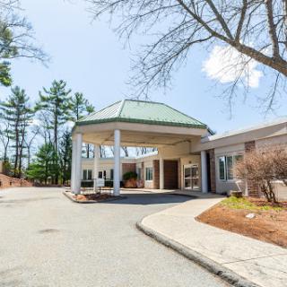 Entrance of a hotel surrounded by trees on a clear day.