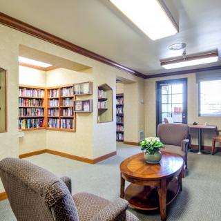 A cozy reading area in a library with bookshelves, comfortable chairs, and a small table.