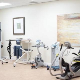 A physical therapy room equipped with stationary bikes and various rehabilitation devices.