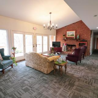 A cozy living room featuring a sofa, armchairs, and a brick fireplace.