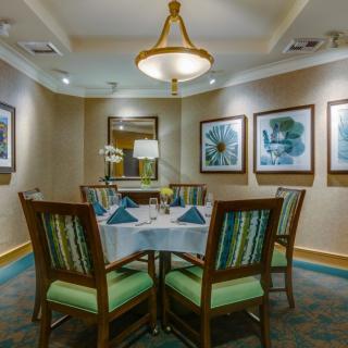 A neatly arranged dining table surrounded by chairs, adorned with elegant decorations and artwork on the walls.