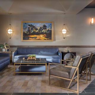 A modern living room with elegant furniture and a scenic painting on the wall.