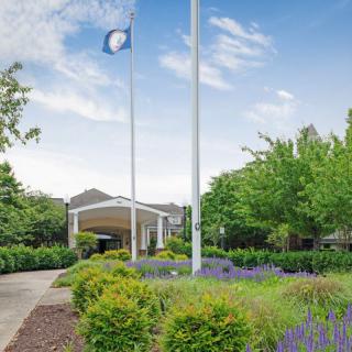 A well-maintained entrance with flags and lush greenery on a clear day.