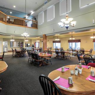 A spacious dining room with neatly arranged tables and warm lighting.