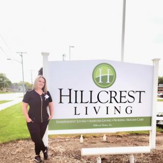 A representative standing next to the Hillcrest Living sign, showcasing the community.