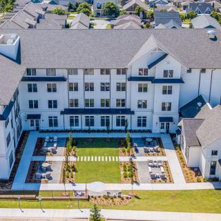 Aerial view of a large, multi-story residential building with a landscaped courtyard.