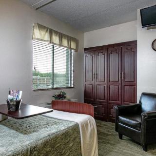 A cozy room with a bed, armchair, and television.