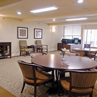 A well-lit dining area with a large table surrounded by chairs, featuring artwork on the walls.