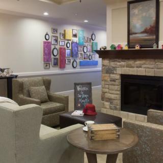 A cozy living room with a fireplace, comfortable seating, and colorful artwork on the walls.