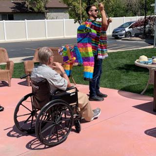 A vibrant community event where a performer engages with attendees, including an individual in a wheelchair, creating a lively atmosphere.