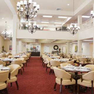 An elegant and spacious dining room interior with chandeliers and neatly arranged tables and chairs.