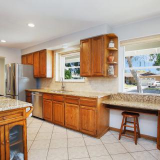 Spacious kitchen with wooden cabinets and granite countertops, featuring stainless steel appliances and a bar seating area.