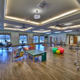 A spacious fitness center featuring various exercise equipment and colorful yoga balls on a wooden floor.
