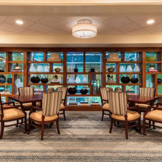 A well-furnished dining area with elegant chairs and tables, surrounded by decorative shelves and ambient lighting.