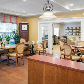 A cozy dining room with neatly arranged tables and chairs, featuring warm lighting and elegant decor.