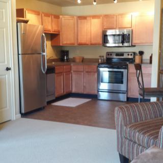 A modern apartment kitchen with stainless steel appliances and wooden cabinets.