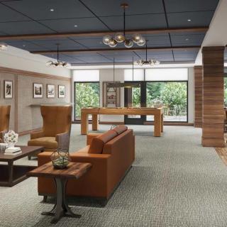 A modern lounge area featuring comfortable seating, stylish lighting, and wood accents with large windows offering a view of the outdoors.