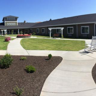 A beautifully landscaped garden with walkways in front of a large building under a clear blue sky.