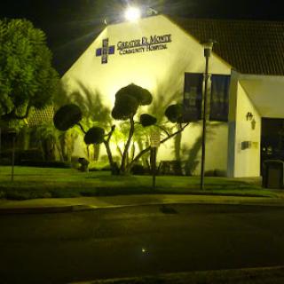 A healthcare building illuminated at night, surrounded by neatly trimmed palm trees.