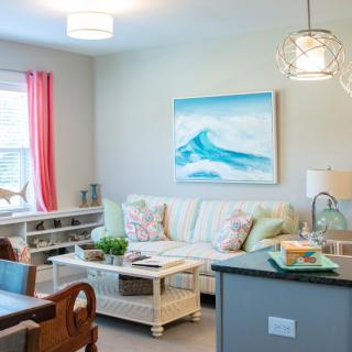 A bright and cozy living room with a sofa, coffee table, and ocean-themed artwork.