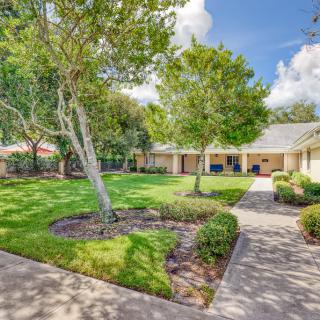 A beautifully landscaped garden with a lush green lawn and well-maintained trees lining a paved pathway.