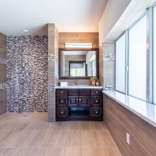 A modern bathroom with a stone feature wall, wooden flooring, and a sleek vanity.