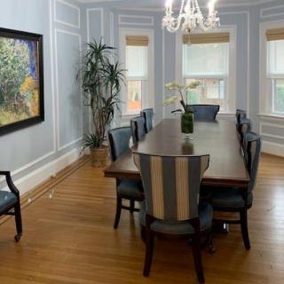 Elegant dining room with a long table, surrounded by chairs and illuminated by a chandelier.