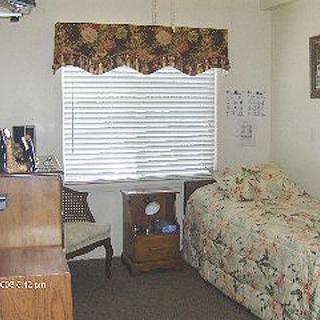 A cozy bedroom with a floral bedspread and a window letting in natural light.