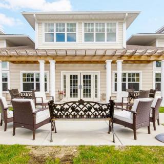 A spacious patio with outdoor furniture and a pergola attached to a residential house.