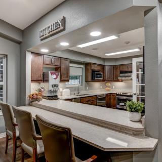 A modern kitchen with wooden cabinetry, a spacious countertop, and comfortable bar stools.