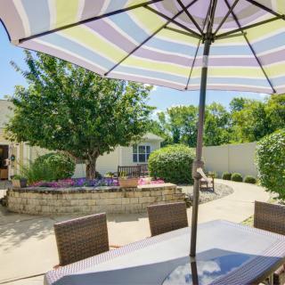 A sunny backyard patio with a table, chairs, and a large umbrella.