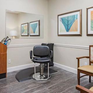 A neatly arranged barbershop interior featuring a styling chair, mirror, and artwork.