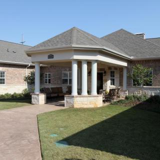 A residential building with a columned entrance and a well-maintained lawn.